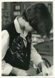 Student in vest uses scissors, date unknown.