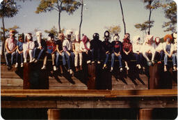 Masked people sit on wall, circa 1980s.