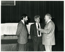Men talk at event, circa 1986-1995.