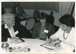 Staff sit at table during conference, circa 1990s.