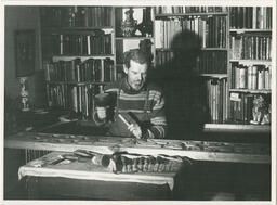 Sculptor carving wood with chisel, circa late 1950's - early 1960's.