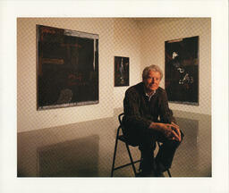 Gordon Smith sits in front of three paintings in the Equinox Gallery, January 1995.